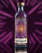 Bottiglia di Mezzanotte London Dry Gin con etichetta viola e oro dai motivi esoterici e alchemici, su sfondo viola. Gin artigianale premium italiano.